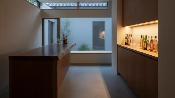 2階セカンドリビングの主役、2.8mの一枚板カウンター。間接照明に照らされたボトルが並ぶ、大人の秘密基地のような内装。